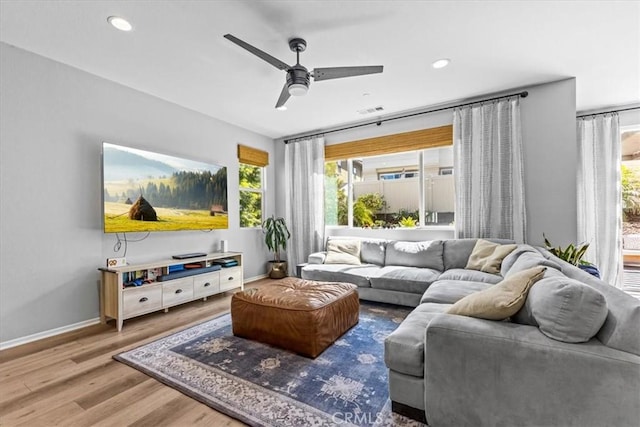 living area with a wealth of natural light, baseboards, and wood finished floors