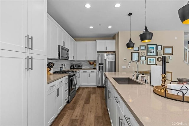 kitchen featuring stainless steel appliances, dark wood finished floors, white cabinets, and a sink