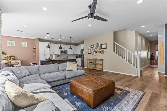 living room with hardwood / wood-style flooring, recessed lighting, visible vents, baseboards, and stairs