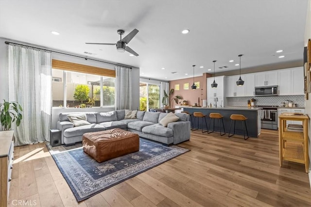 living room with light wood finished floors, a ceiling fan, and recessed lighting