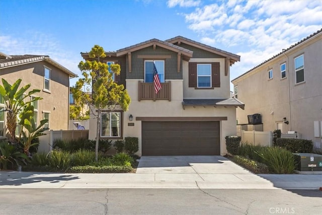 view of front of house with driveway, a garage, fence, and stucco siding