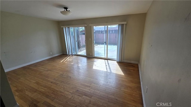 empty room featuring hardwood / wood-style flooring and baseboards