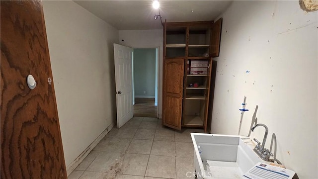 interior space with light tile patterned floors, a sink, and baseboards