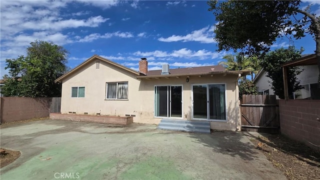 back of house featuring a chimney, stucco siding, entry steps, a patio area, and fence