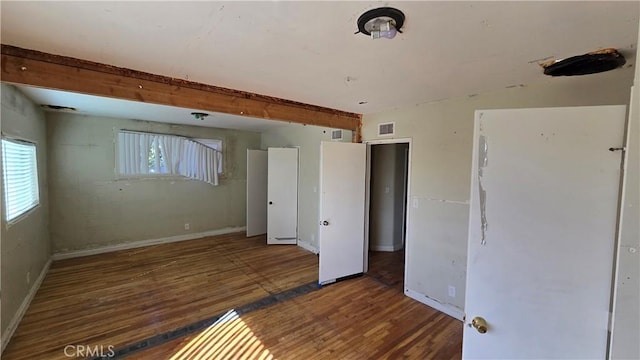 spare room featuring visible vents, baseboards, and wood finished floors