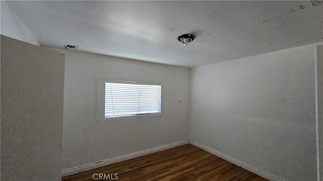 unfurnished room with dark wood-style floors and baseboards