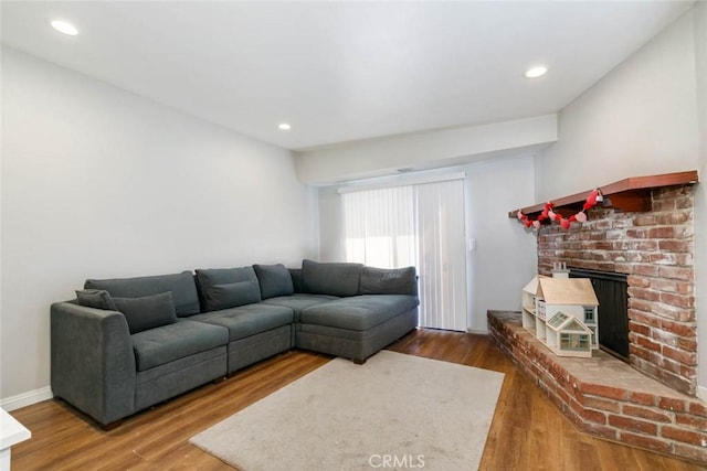 living area featuring baseboards, a fireplace, wood finished floors, and recessed lighting