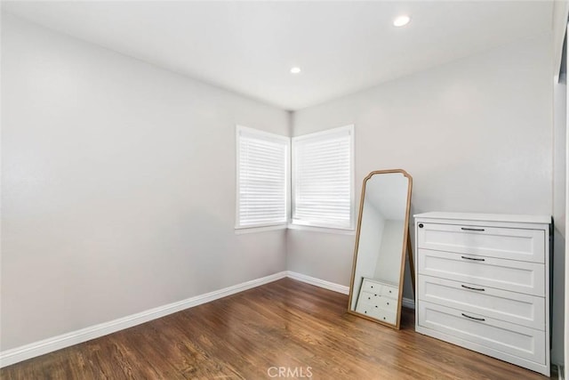 unfurnished bedroom featuring baseboards, wood finished floors, and recessed lighting