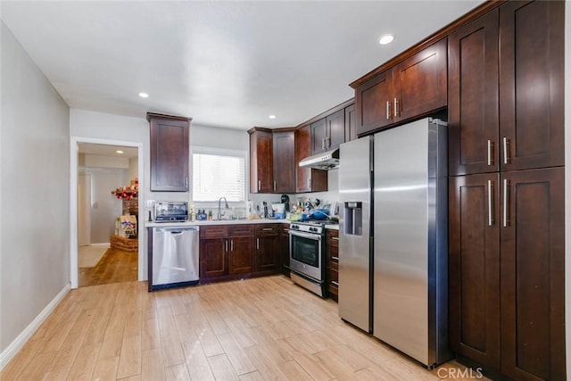 kitchen featuring appliances with stainless steel finishes, light wood-type flooring, dark brown cabinetry, and under cabinet range hood