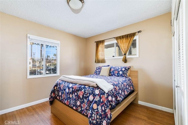 bedroom featuring a textured ceiling, wood-type flooring, and baseboards