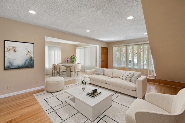 living area with recessed lighting, a textured ceiling, baseboards, and wood finished floors