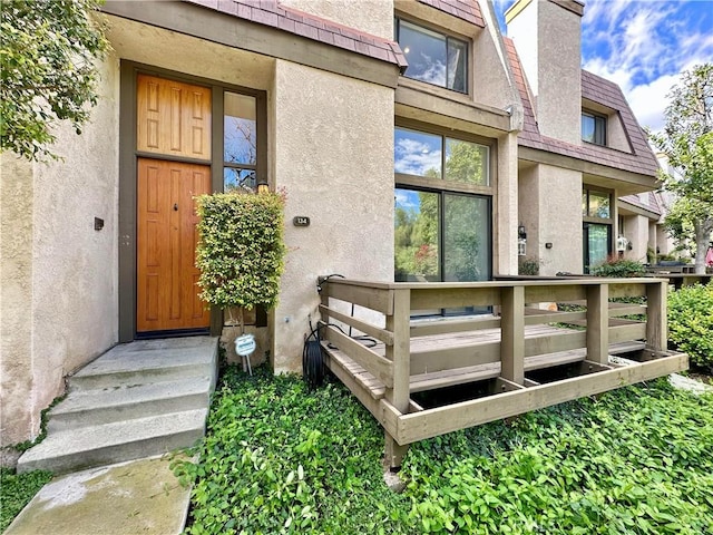 entrance to property featuring a chimney and stucco siding