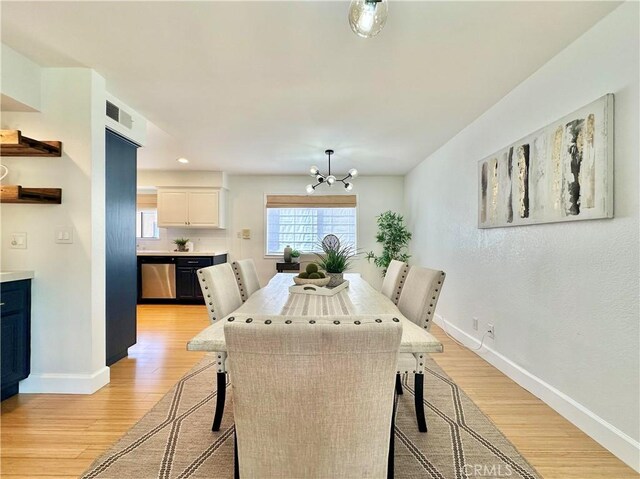 dining area featuring a notable chandelier, baseboards, visible vents, and light wood-style floors