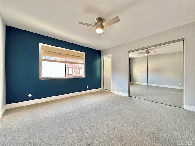 unfurnished bedroom with carpet floors, a closet, a ceiling fan, and baseboards