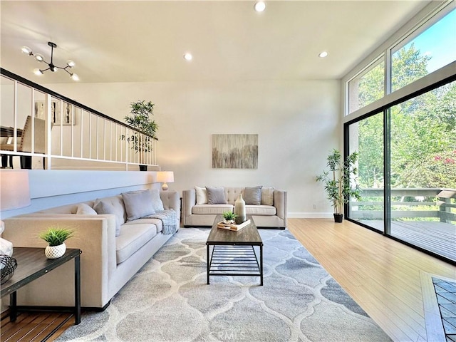 living room featuring recessed lighting, an inviting chandelier, wood finished floors, a wall of windows, and baseboards