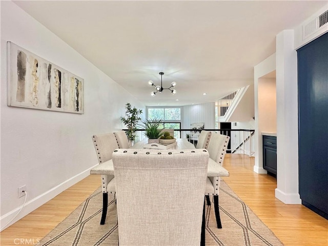 dining area featuring baseboards, light wood-type flooring, visible vents, and a notable chandelier