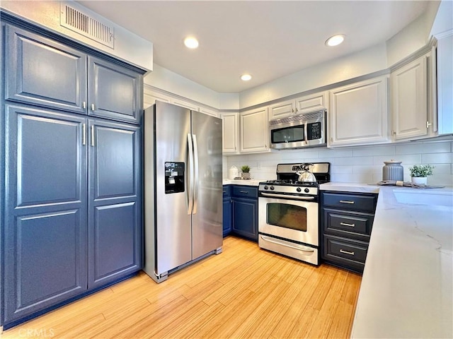 kitchen with stainless steel appliances, tasteful backsplash, visible vents, and light wood-style floors