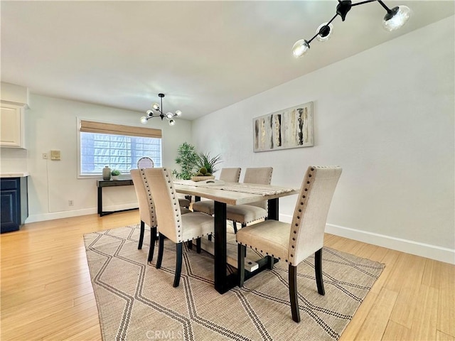 dining room with a chandelier, light wood-type flooring, and baseboards