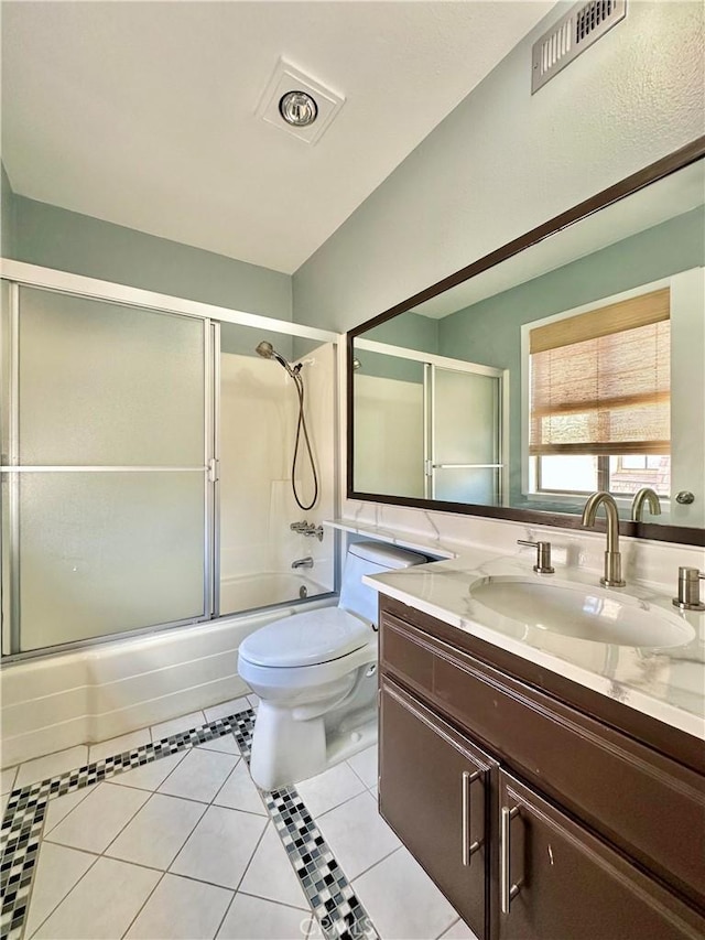 bathroom featuring visible vents, toilet, combined bath / shower with glass door, vanity, and tile patterned floors