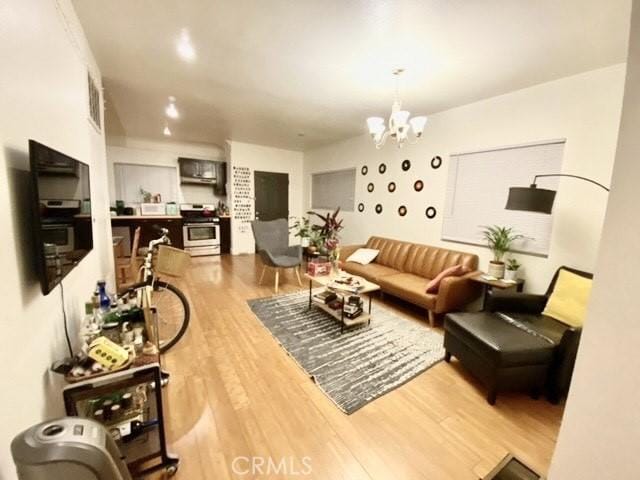 living room with visible vents, an inviting chandelier, and wood finished floors