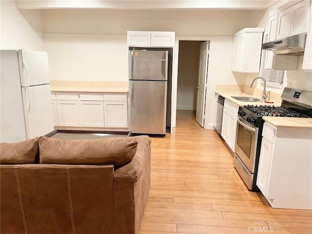 kitchen featuring a sink, light countertops, light wood-style floors, under cabinet range hood, and appliances with stainless steel finishes