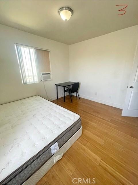 bedroom with light wood-type flooring, baseboards, and cooling unit