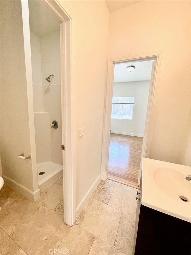 bathroom with vanity, a shower stall, and baseboards