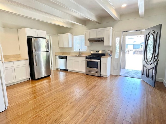 kitchen with under cabinet range hood, a sink, white cabinetry, appliances with stainless steel finishes, and light wood finished floors