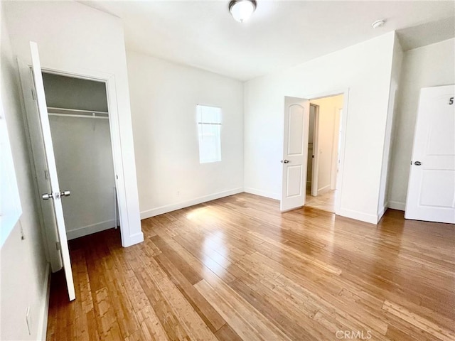 unfurnished bedroom featuring a closet, light wood-type flooring, and baseboards