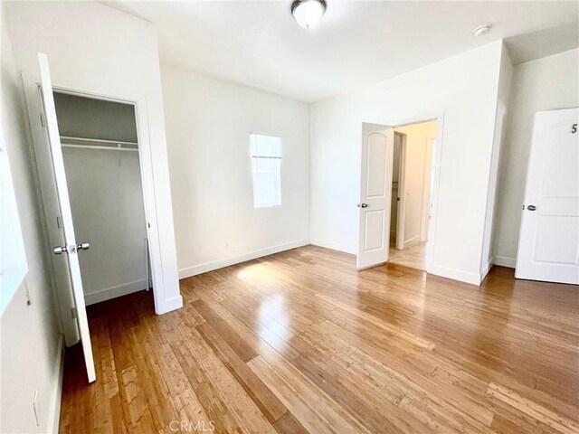 1238 W 35th St, Los Angeles, CA 90007 - unfurnished bedroom featuring light wood-style flooring, a closet, and baseboards