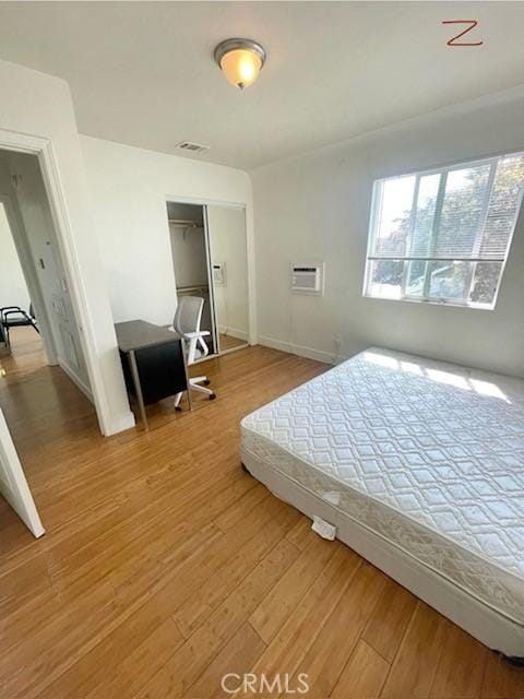 bedroom with light wood-style floors, baseboards, and a closet