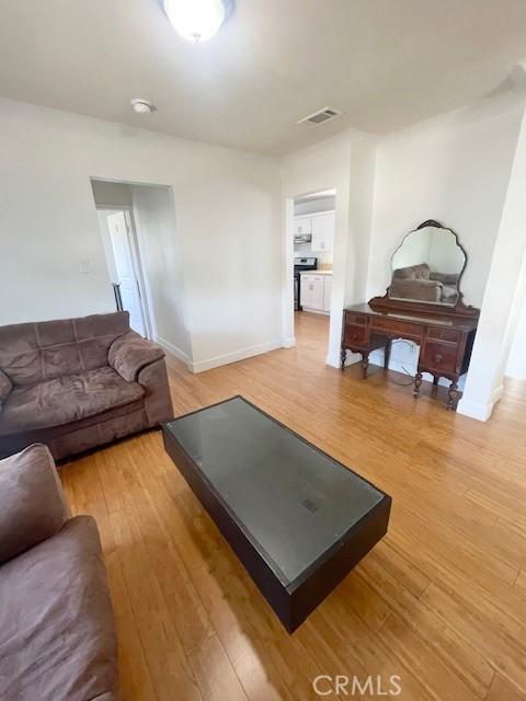 living room with light wood-style flooring, baseboards, and visible vents