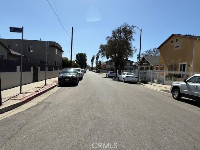 view of road featuring a residential view, curbs, sidewalks, and street lighting