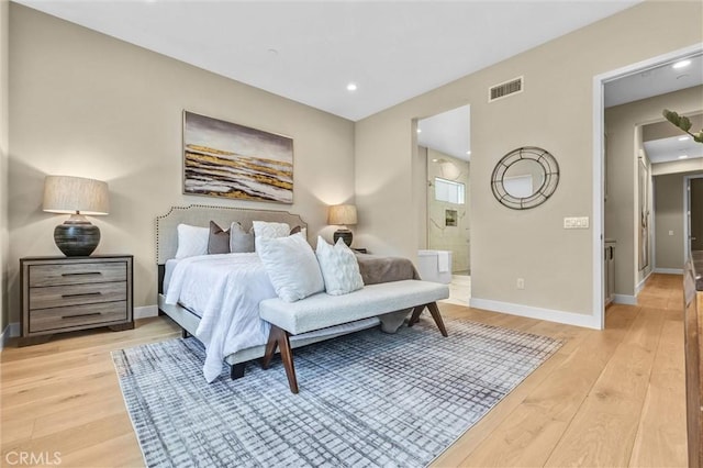 bedroom featuring light wood-type flooring, visible vents, connected bathroom, and baseboards