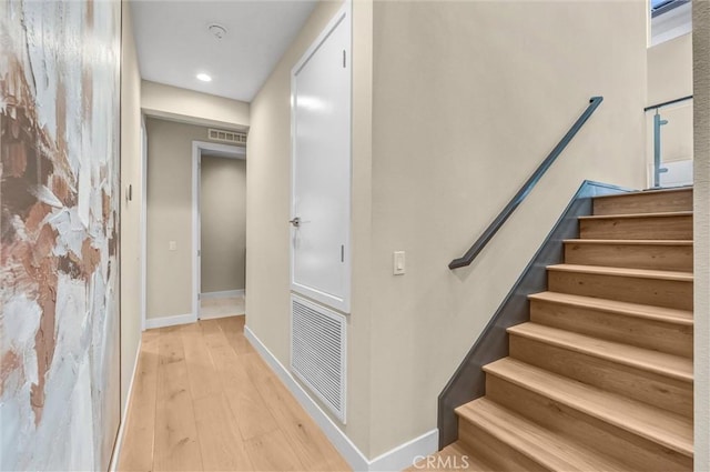 stairway featuring baseboards, visible vents, and wood finished floors