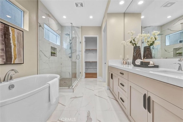 bathroom featuring marble finish floor, a soaking tub, a sink, and a shower stall