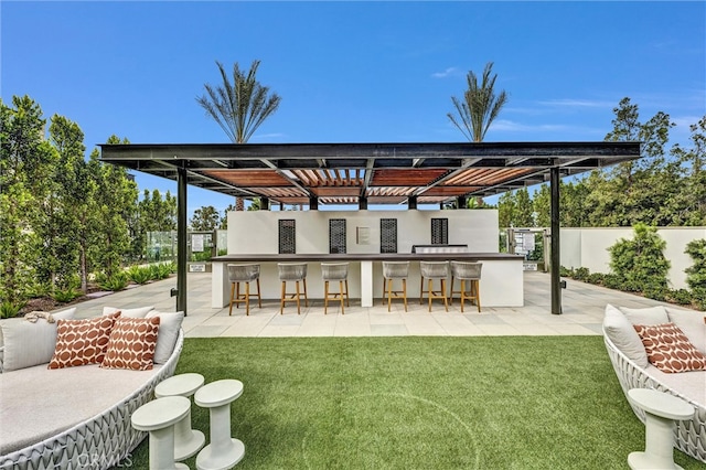 back of property featuring a yard, stucco siding, a patio area, fence, and an outdoor bar