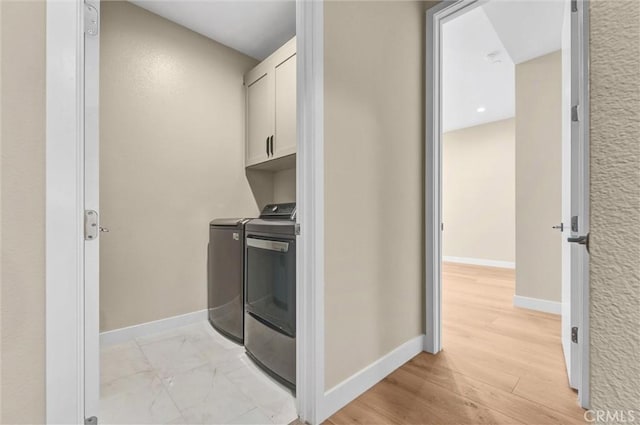 kitchen with baseboards, white cabinets, light wood-style flooring, independent washer and dryer, and light countertops