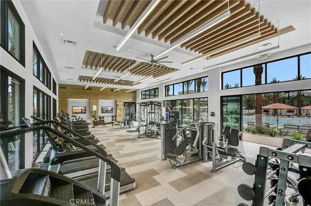 workout area featuring a healthy amount of sunlight, visible vents, wood walls, and a high ceiling