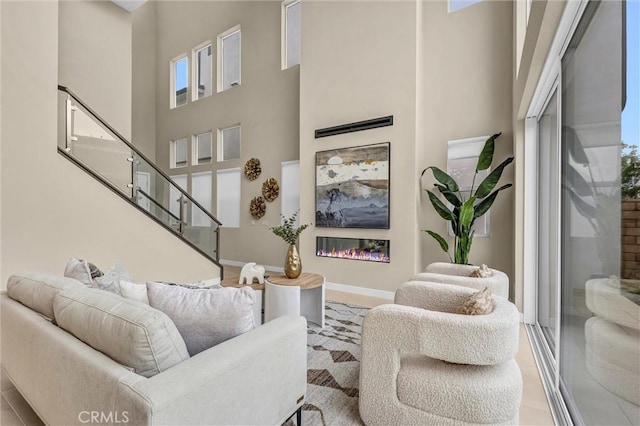 living room featuring a high ceiling, baseboards, and a glass covered fireplace