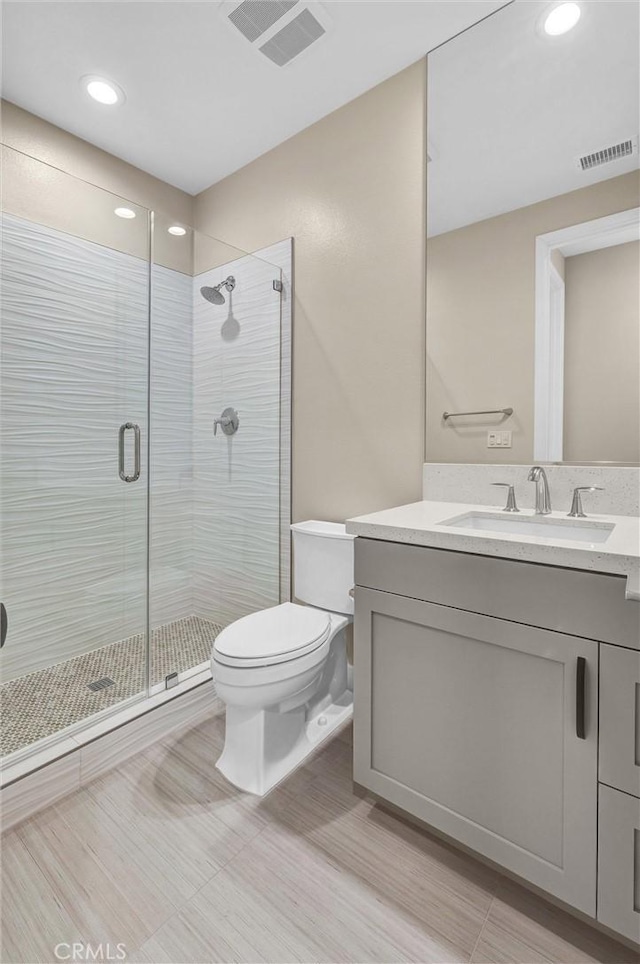 full bathroom featuring a stall shower, visible vents, vanity, and toilet