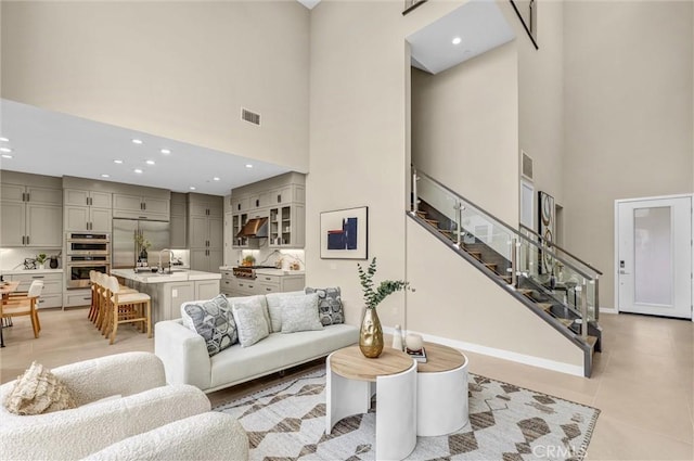 living area featuring recessed lighting, a high ceiling, visible vents, baseboards, and stairs