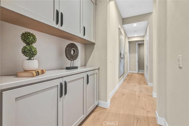 corridor featuring light wood-type flooring and baseboards