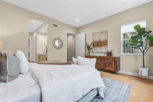 bedroom featuring light wood finished floors, recessed lighting, visible vents, ensuite bath, and baseboards