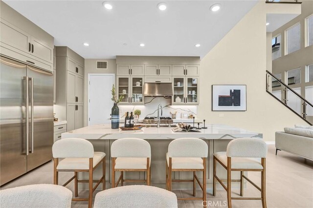 1155 Poppy Ct, Montebello, CA 90640 - kitchen featuring built in refrigerator, under cabinet range hood, glass insert cabinets, a kitchen bar, and recessed lighting