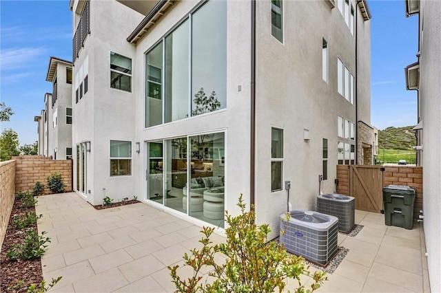 back of property featuring central AC, a patio area, fence, and stucco siding