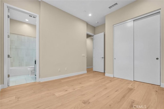 unfurnished bedroom featuring baseboards, visible vents, wood finished floors, ensuite bathroom, and recessed lighting