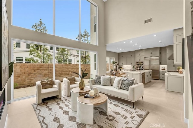 living area with recessed lighting, a high ceiling, visible vents, and light tile patterned flooring