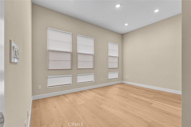 empty room featuring light wood-type flooring, baseboards, and recessed lighting