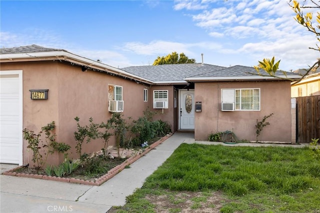 view of front of house featuring a front yard, an attached garage, fence, and stucco siding